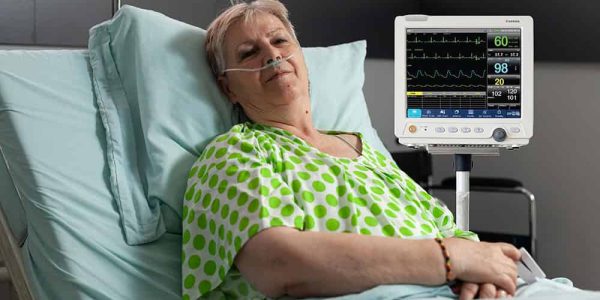 Portrait of sick pensioner woman looking into camera while resting in bed recovering after medical surgery in hospital ward. Hospitalized patient waiting for healthcare treatment during examination