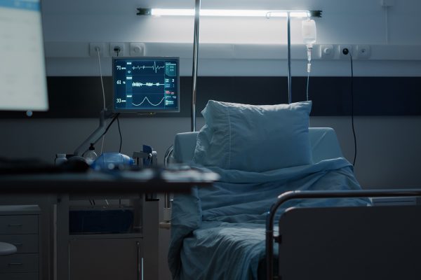 Empty hospital ward designed with medical equipment used as treatment for disease, illness, health problems. Intensive care room with medical tools, monitor, IV drip bag and oxygen tube